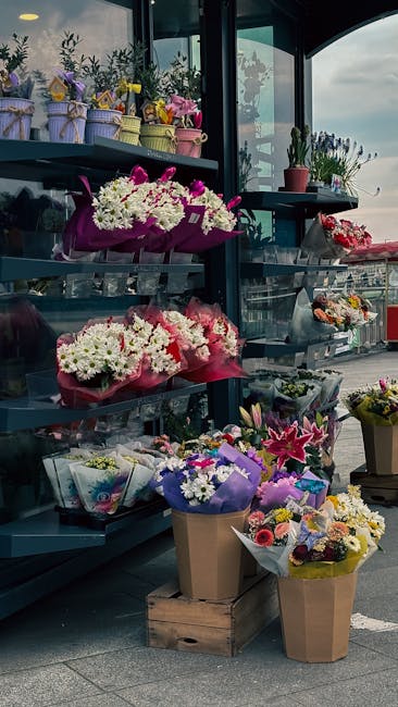 A display of various floral arrangements at a flower shop near Upminster Station, featuring vibrant bouquets of mixed seasonal flowers including white chrysanthemums, pink lilies, and purple and yello